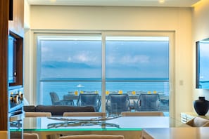 Ein Zimmer mit einer großen Schiebeglastür, die auf einen Balkon mit Meerblick führt.