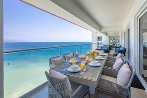 Ein Balkon mit Esstisch, gedeckt für ein Frühstück, mit Blick auf das klare, blaue Meer.