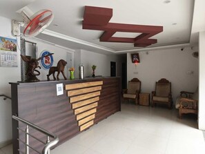 A reception desk with a wooden finish, a fan, and a wall-mounted clock. - Hotel O Erumeli Bus Terminal Kottayam (Kanjirappally)
