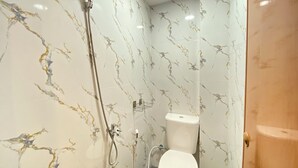 Ein Badezimmer mit Dusche, Toilette und Wänden mit Marmoroptik.