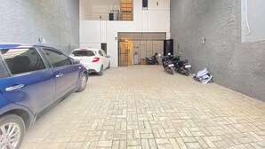 Ein gepflasterter Innenhof mit zwei Autos und mehreren Motorrädern.