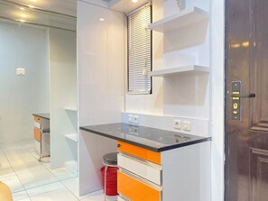 Una cocina moderna con encimera negra, armarios blancos y un cubo de basura rojo.
