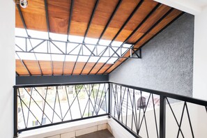 Een balkon met houten plafond en metalen hekwerk.
