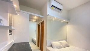 Ein modernes Hotelzimmer mit Bett, Nachttisch und integrierter Klimaanlage.