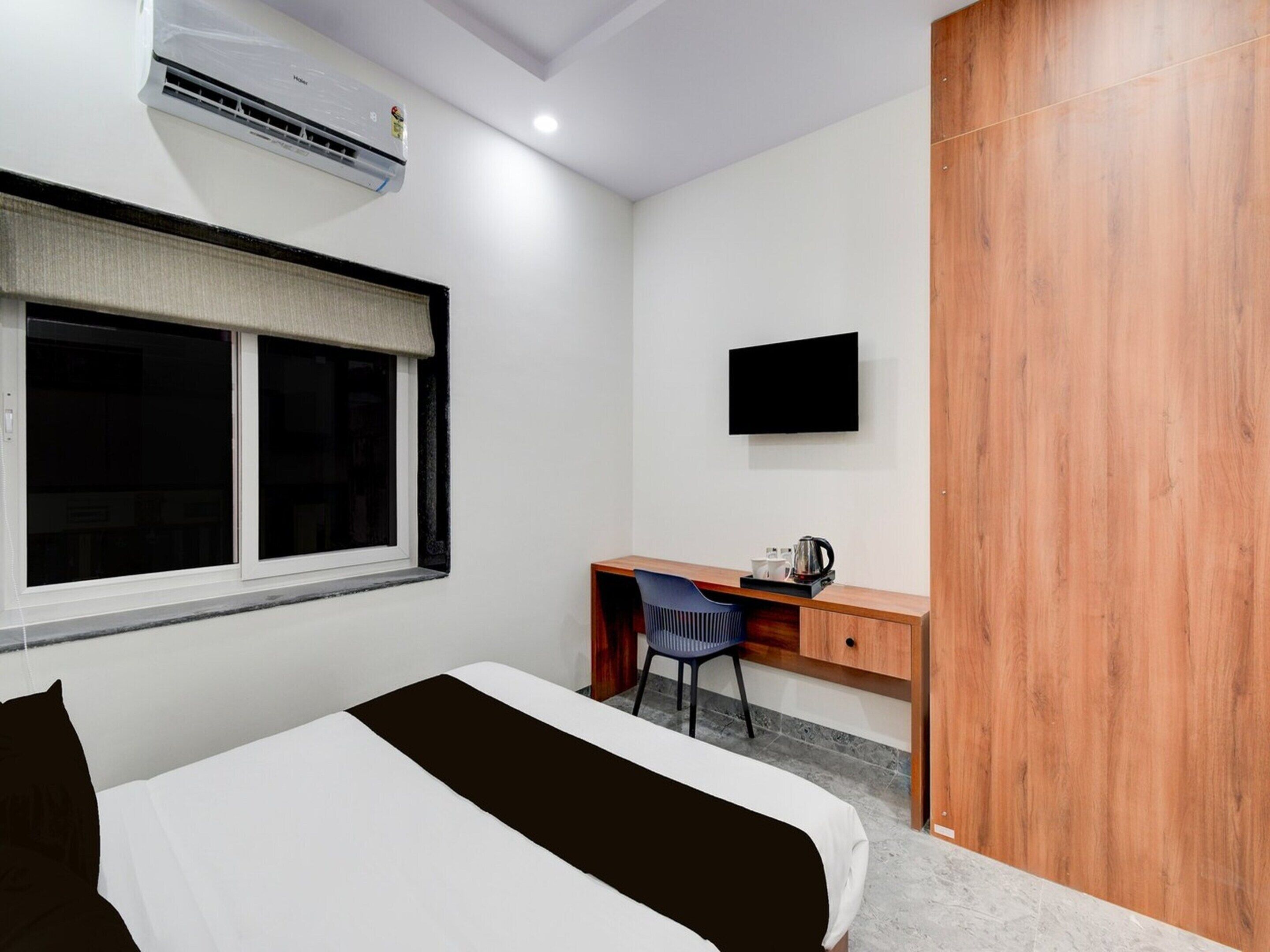 Una camera d'albergo con un letto, una scrivania con una sedia, una televisione e un climatizzatore.