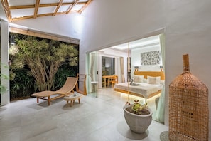 A modern interior with a lounge chair, a potted plant, and a bed in a well-lit room. - Bingin Villas: Luxury, Concierge &  Security (Badung)
