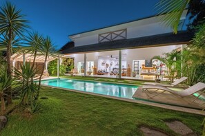Uma casa moderna com piscina, área de estar externa e interior bem iluminado.