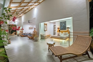 A modern interior with a high ceiling, a wicker lounge chair, a sofa, and a glass partition. - Bingin Villas: Luxury, Concierge &  Security (Badung)