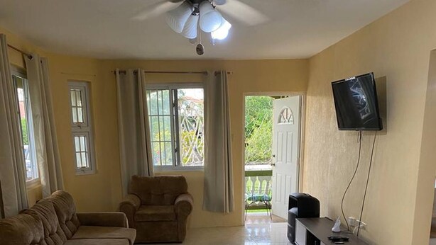 A living room with a ceiling fan, a TV, and a balcony. - TJ Guest House - Jamaica (Spanish Town)
