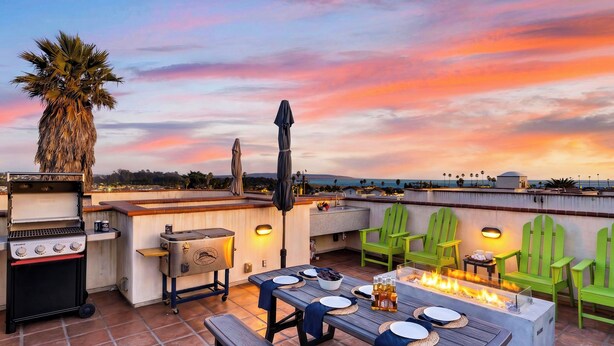 Eine Terrasse im Freien mit Grill, Sitzgelegenheiten und Feuerstelle.