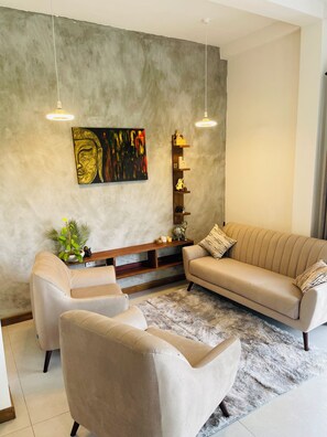 A modern living room with a sofa, armchairs, a coffee table, and a decorative shelf. - Villa White Homes (Unawatuna)