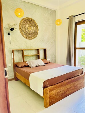 Een slaapkamer met een houten bed, een muurventilator en een decoratief wandobject.