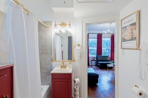 Un baño con tocador, espejo y cortina de ducha.