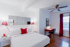 Una habitación de hotel con cama, escritorio, silla y ventilador de techo.