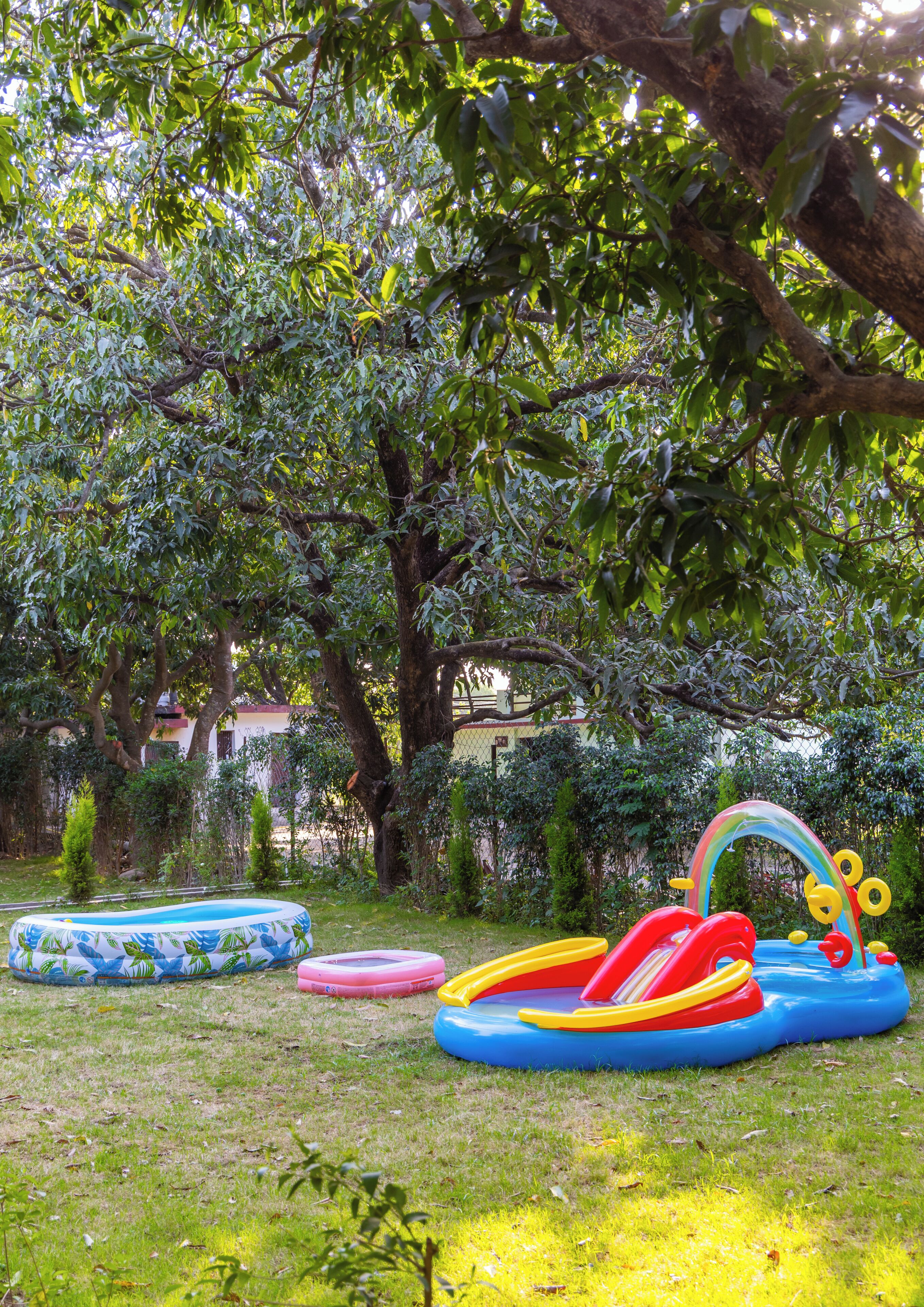 A grassy area with inflatable play equipment and trees.