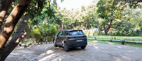 A vehicle parked in a natural setting with trees and a dirt path.