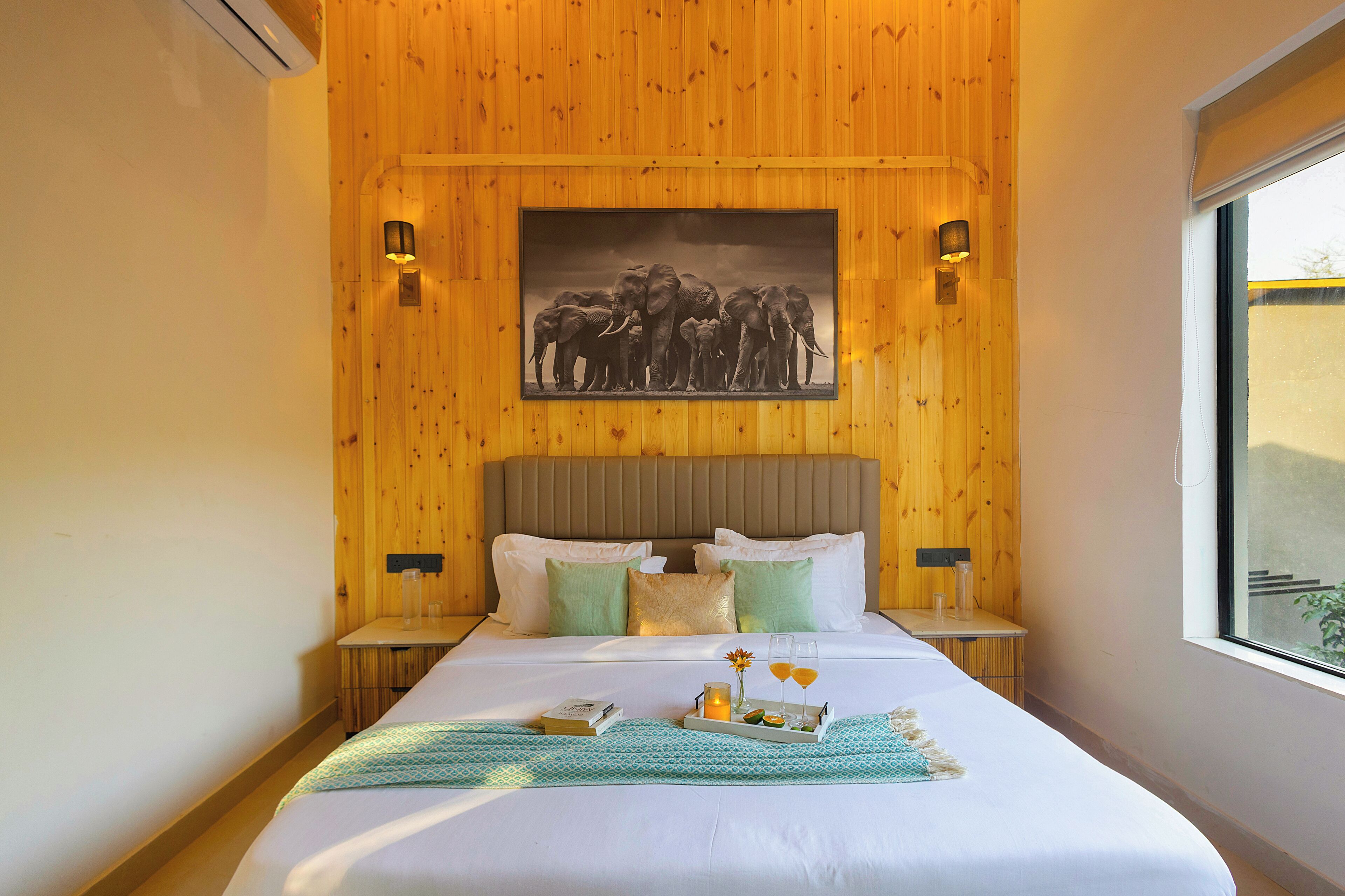 A wooden-paneled room with a bed, pillows, bedside tables, and a framed picture on the wall.