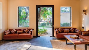 A spacious room with two sofas, a coffee table, and a view through a door. - Sylvaara Suites by ELIVAAS Jim Corbett (Ramnagar)