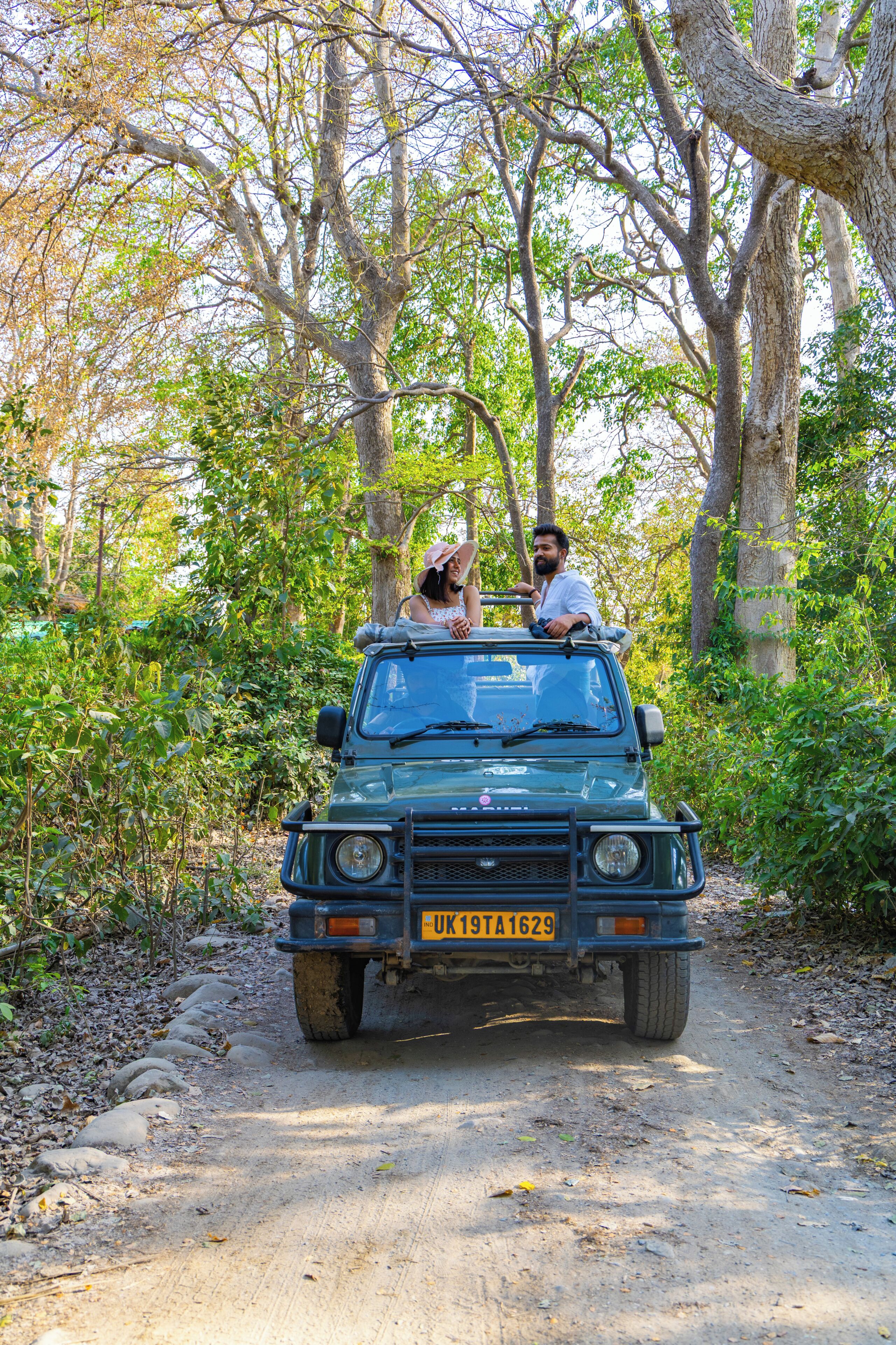 A vehicle on a dirt path surrounded by trees.