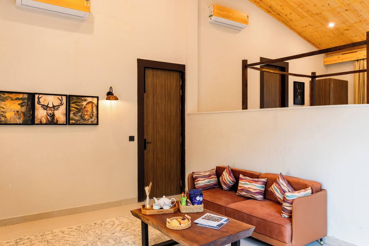 A cozy living area with a sofa, a coffee table with items, a door, and wall art.