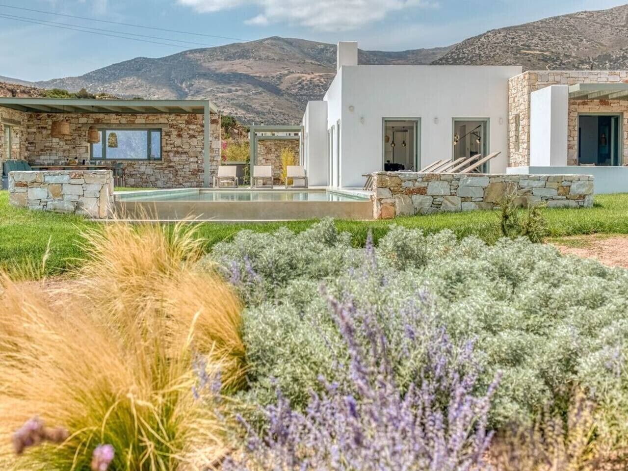Ein modernes Gebäude mit Natursteinfassade, einem Pool und einem Garten mit verschiedenen Pflanzen.