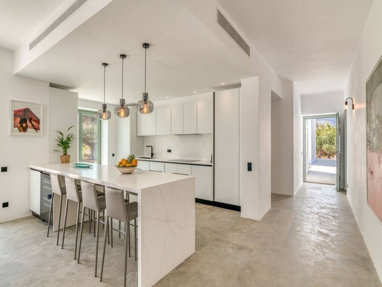 A modern kitchen with a central island, pendant lighting, and a view to the outdoors.