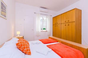 Ein Schlafzimmer mit einem Bett, einem Kleiderschrank, einem Fenster mit Vorhängen und einer Nachttischlampe.