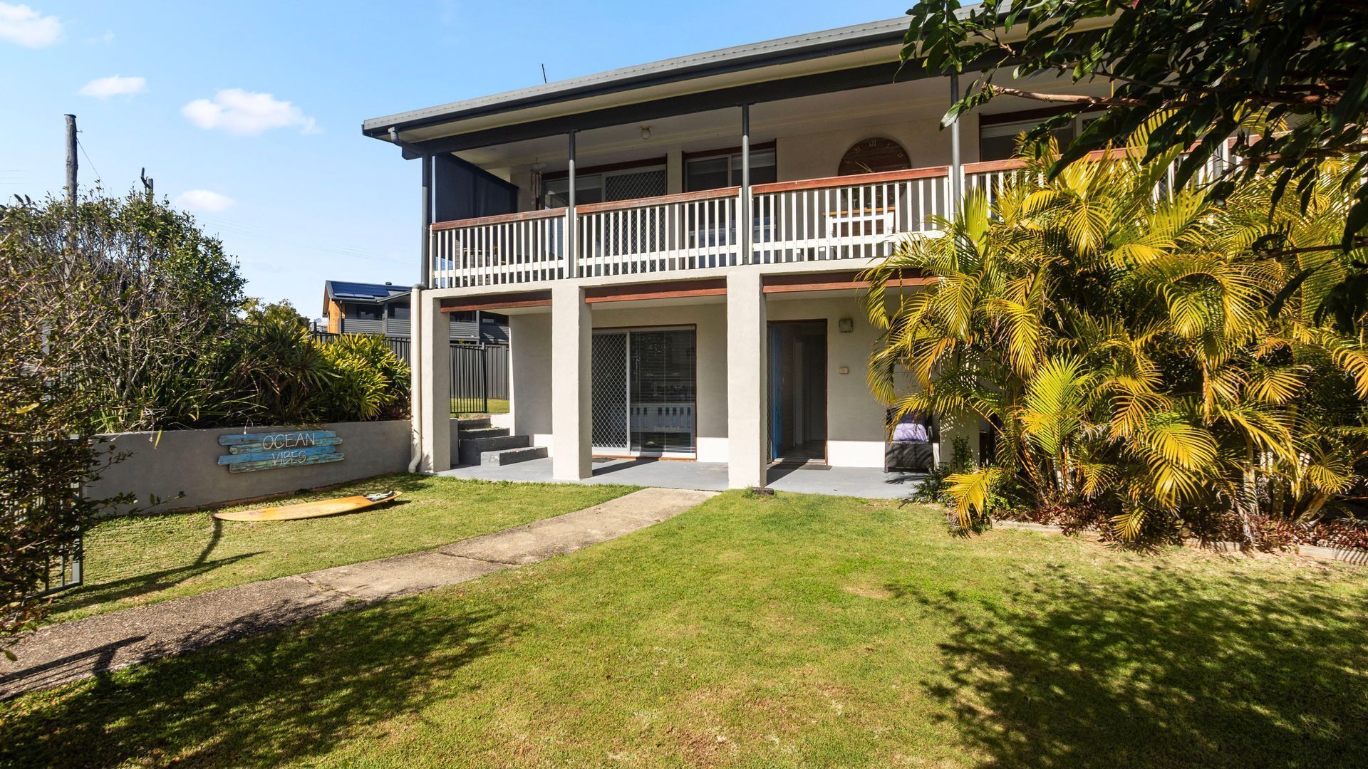 A two-story building with a balcony, a covered porch, and a well-maintained lawn.
