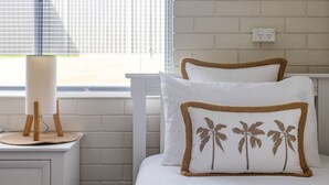 A bed with white bedding and two pillows with woven edges and palm tree designs. - Ocean Vibes - Your Ultimate Scotts Head Coastal Escape (Scotts Head)