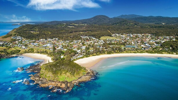 An aerial view of a coastal town with a beach, clear blue waters, and a mountainous backdrop. - Ocean Vibes - Your Ultimate Scotts Head Coastal Escape (Scotts Head)