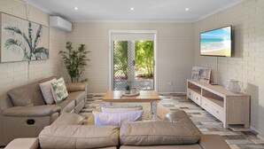 A modern living room with a sofa, coffee table, and TV. - Ocean Vibes - Your Ultimate Scotts Head Coastal Escape (Scotts Head)