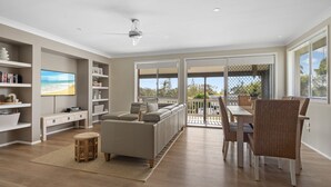 A spacious living room with a sofa, TV, and dining area. - Ocean Vibes - Your Ultimate Scotts Head Coastal Escape (Scotts Head)