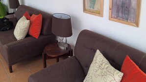 Ett vardagsrum med två soffor, en lampa och flera inramade konstverk på väggen.
