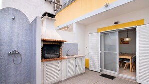 Una cocina compacta con horno integrado, un lavamanos y una zona de comedor con mesa y sillas.