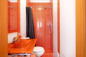 A bathroom with a red-tiled shower, a white toilet, and an orange sink. - Captivating Holiday Home in Manta Rota with Swimming Pool (Manta Rota)