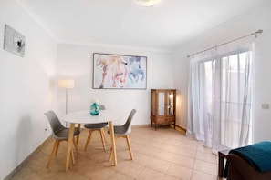 A room with a dining table, chairs, a cabinet, and a large window with curtains. - Captivating Holiday Home in Manta Rota with Swimming Pool (Manta Rota)