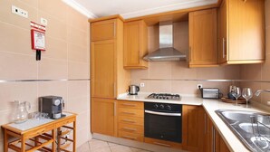 Una cocina con armarios de madera, estufa, lavavajillas y pileta.