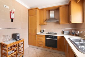 A kitchen with wooden cabinets, a stove, a dishwasher, and a sink. - Captivating Holiday Home in Manta Rota with Swimming Pool (Manta Rota)