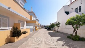 Una calle estrecha flanqueada por edificios, con una acera pavimentada y un coche estacionado.