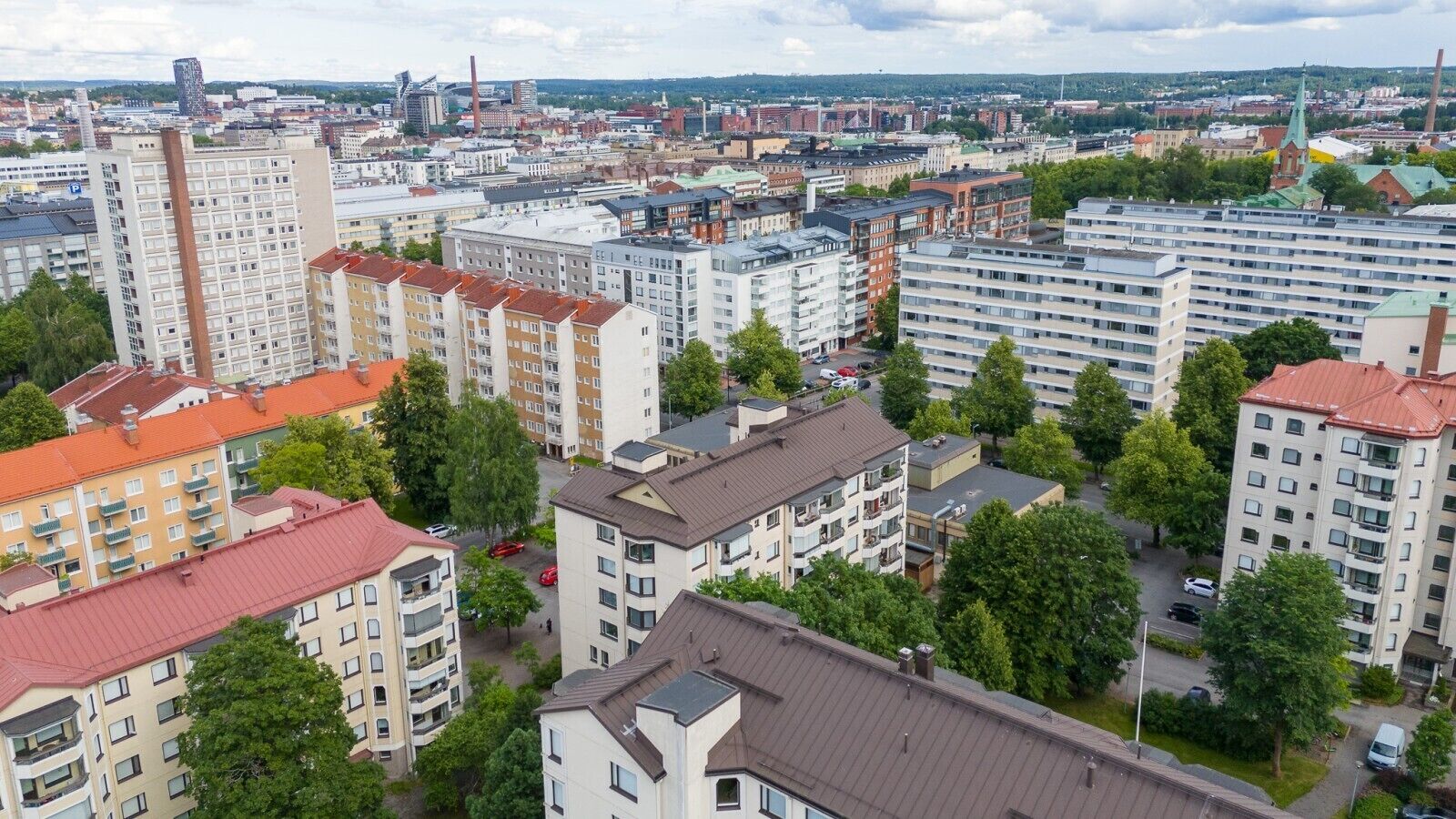 A high-rise residential building complex with multiple apartment buildings, surrounded by greenery and other structures.