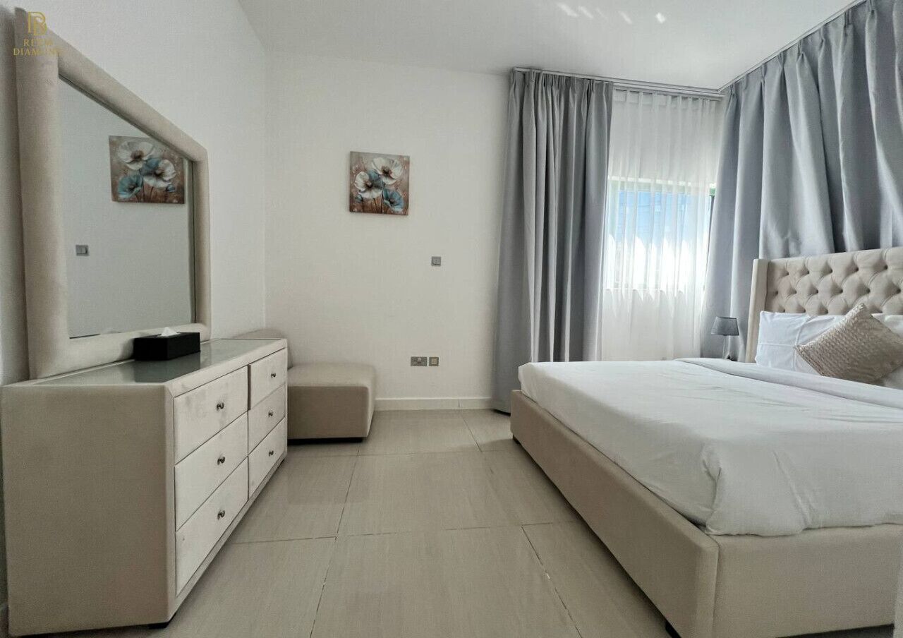 A bedroom with a bed, a dresser, a nightstand, and two wall-mounted paintings.