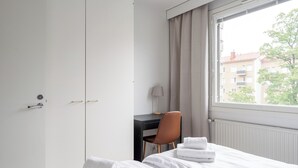 Ein Hotelzimmer mit Bett, Schreibtisch, Stuhl und einem fenster mit Vorhängen.