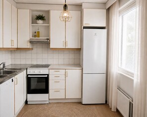 A modern kitchen with white cabinetry, a built-in oven, a refrigerator, and a pendant light. - Stylish 1BR Apt with Sauna & Balcony (Tampere)