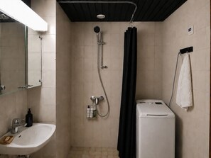 A bathroom with a shower, a sink, a mirror, a towel rack, and a washing machine. - Stylish 1BR Apt with Sauna & Balcony (Tampere)