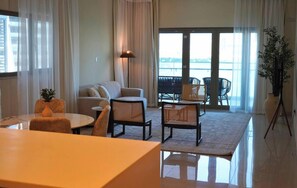 Un salon moderne comprenant un canapé, des fauteuils, une table à manger et un balcon avec des sièges d’extérieur.