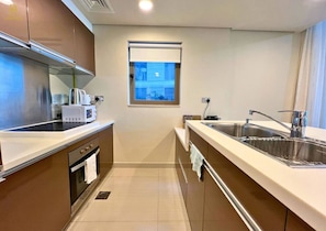 A compact kitchen with a microwave, oven, sink, and window. - Elegant 2BR Retreat on Al Reem Island (Abu Dhabi)