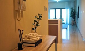 Un couloir avec une table en bois, un téléphone blanc, une plante en pot et un livre.