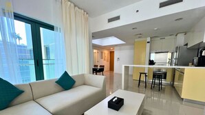 Ein modernes Hotelzimmer mit Sofa, Couchtisch, Küchenzeile und Blick auf die Stadt.