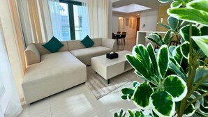 Ein modernes Wohnzimmer mit einer Couch, einem Couchtisch und einem Essbereich im Hintergrund.