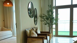 Ein Wohnzimmer mit einer Couch, zwei Sesseln, einem großen Fenster mit Blick und einer Pendelleuchte.